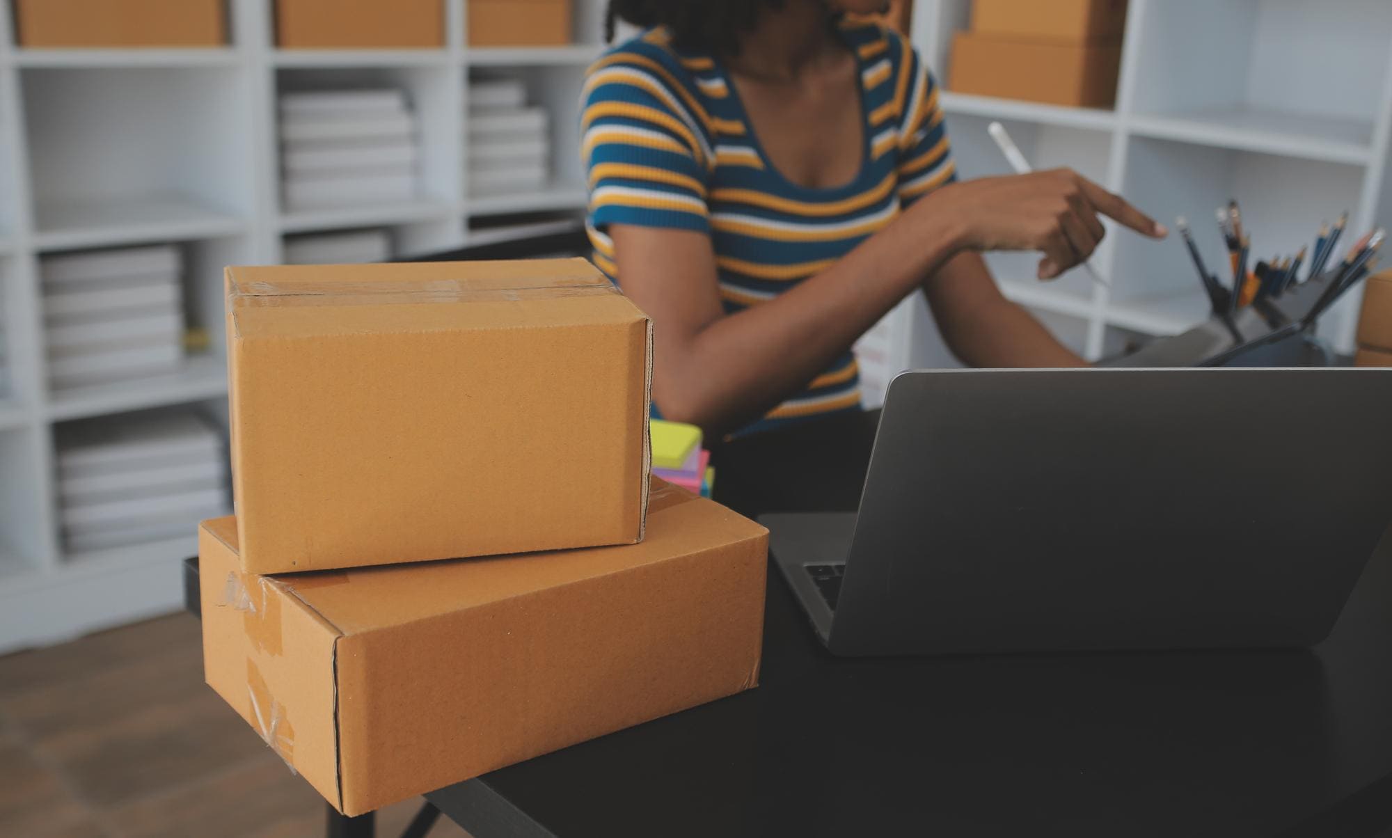mulher de negócios gerenciando vendas de ecommerce em escritório com caixas
